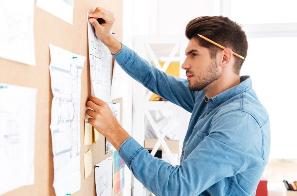 Man organizing papers on wall